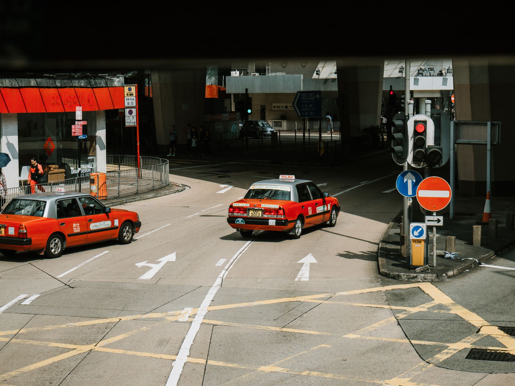 From above of red taxi cars driving on asphalt street near crossroad in modern city district on sunny day