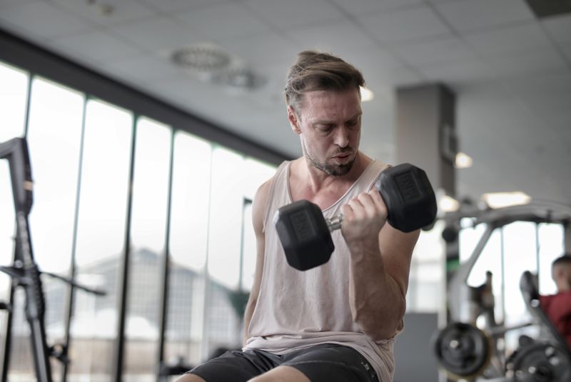 Adult man focused on lifting a dumbbell in a gym — functional strength training after 40