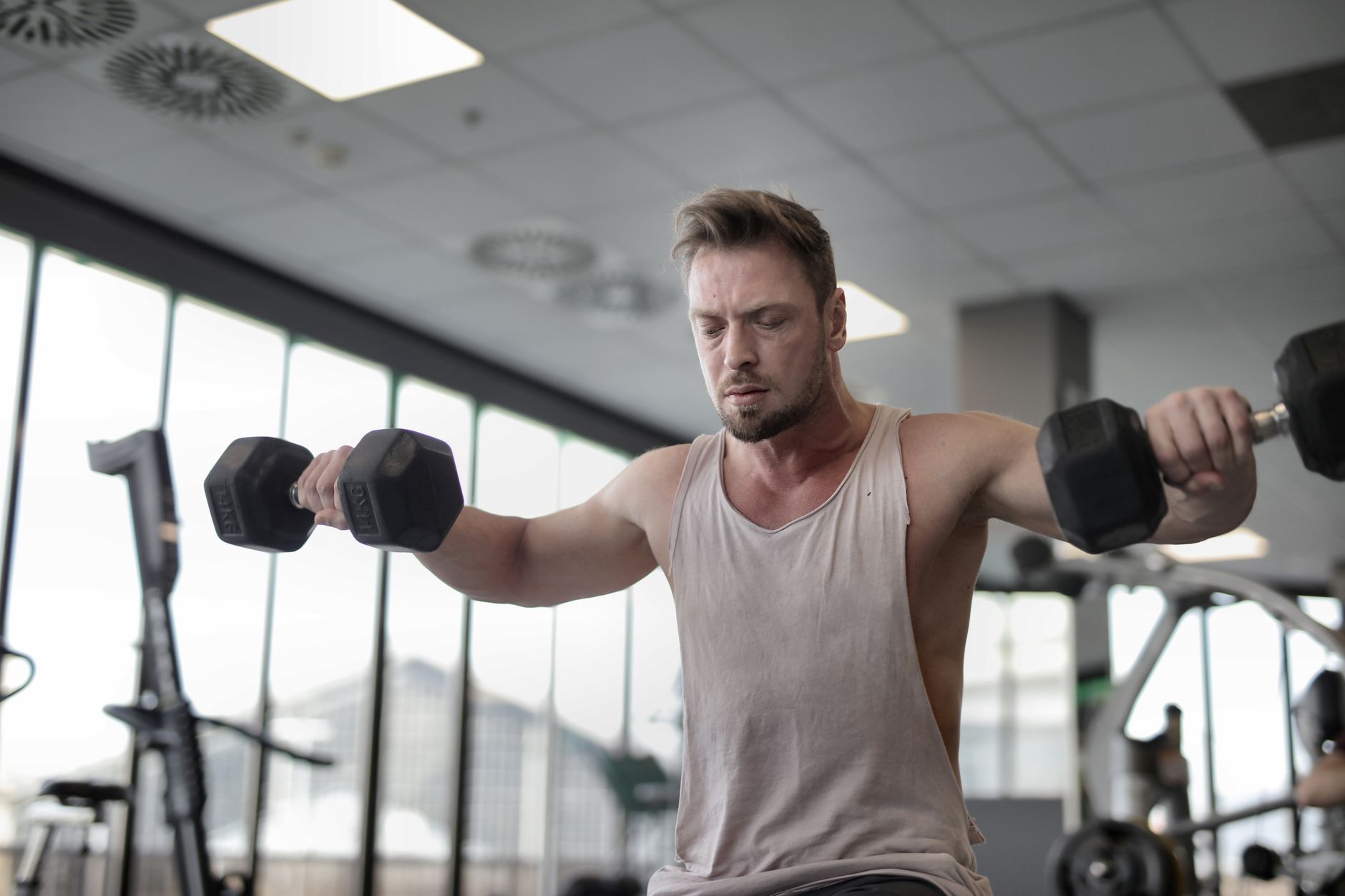 Focused man working out with dumbbells at gym showcasing strength and determination