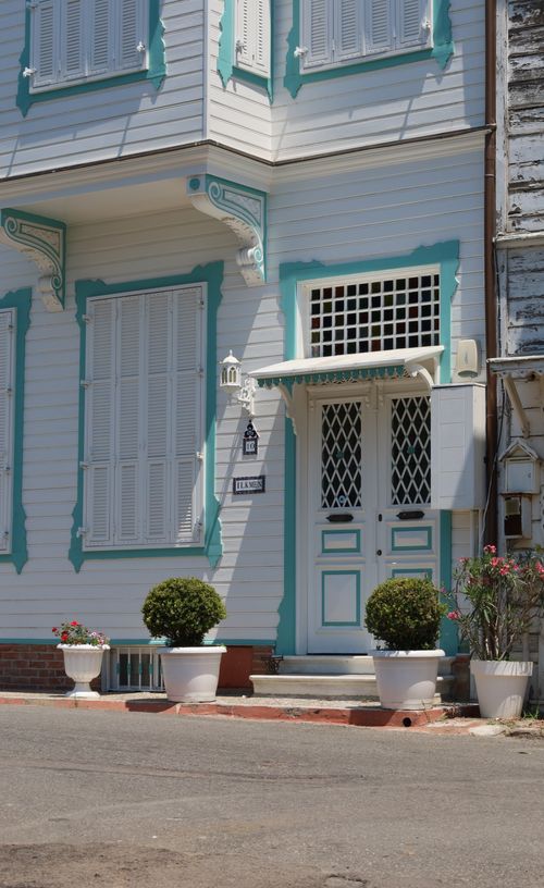 Free A picturesque Victorian-style house with turquoise accents and potted plants on the street. Stock Photo