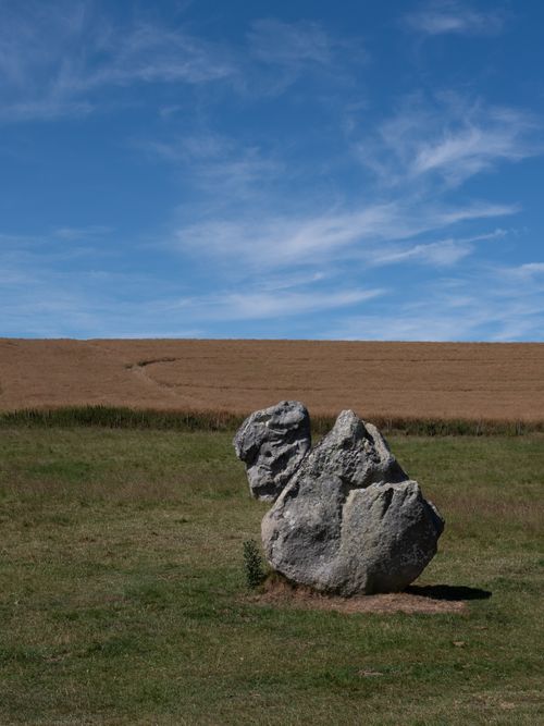 Free A solitary rock formation in a vast, open field under a vivid blue sky. Stock Photo
