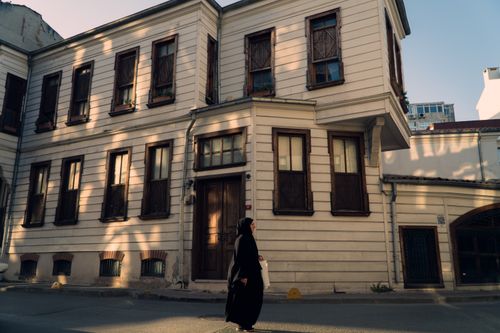 Free A woman walks past a historic building in the Fatih district of Istanbul, Türkiye, in the late afternoon light. Stock Photo