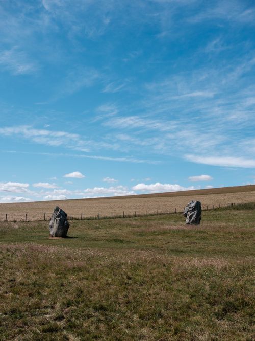 Free Two ancient standing stones in a grassy field under a bright blue sky. Stock Photo