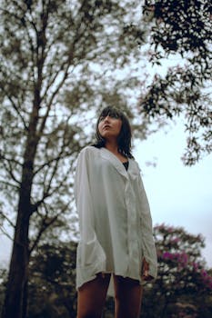 森林里站着一个穿着超大号白衬衫的年轻女子肖像