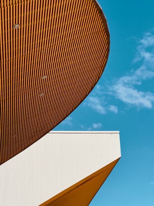 Free A modern architectural structure with dynamic lines set against a clear blue sky, showcasing innovative design. Stock Photo