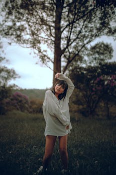 日落时分，一位身穿白衬衫的年轻女子在宁静的自然环境中优雅地摆着姿势