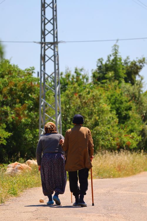 Free An elderly couple walks together on a rural path surrounded by greenery. Stock Photo