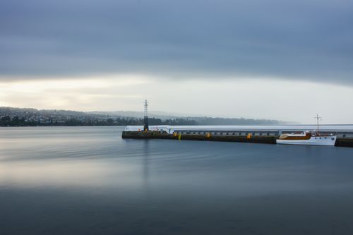 Free Serene scene of a boat docked at the pier in Jönköping under a cloudy sky. Stock Photo