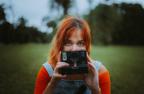 無料 黒のカメラを保持している赤い長袖シャツの女の子 写真素材
