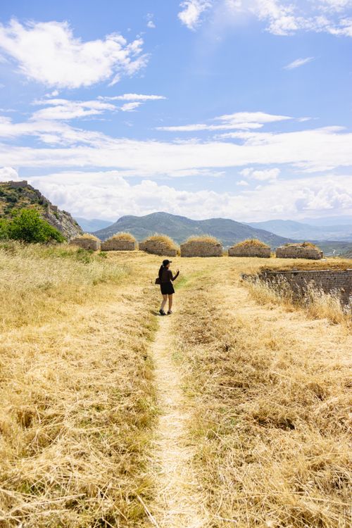 Free A traveler explores the picturesque landscape in Greece, surrounded by dry grass and distant hills. Stock Photo