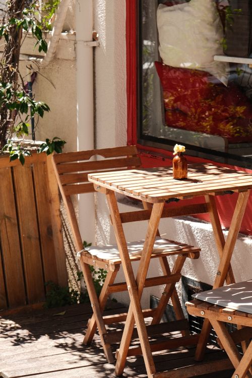 Free Charming outdoor cafe with wooden table and chairs under sunlight, perfect for relaxation. Stock Photo