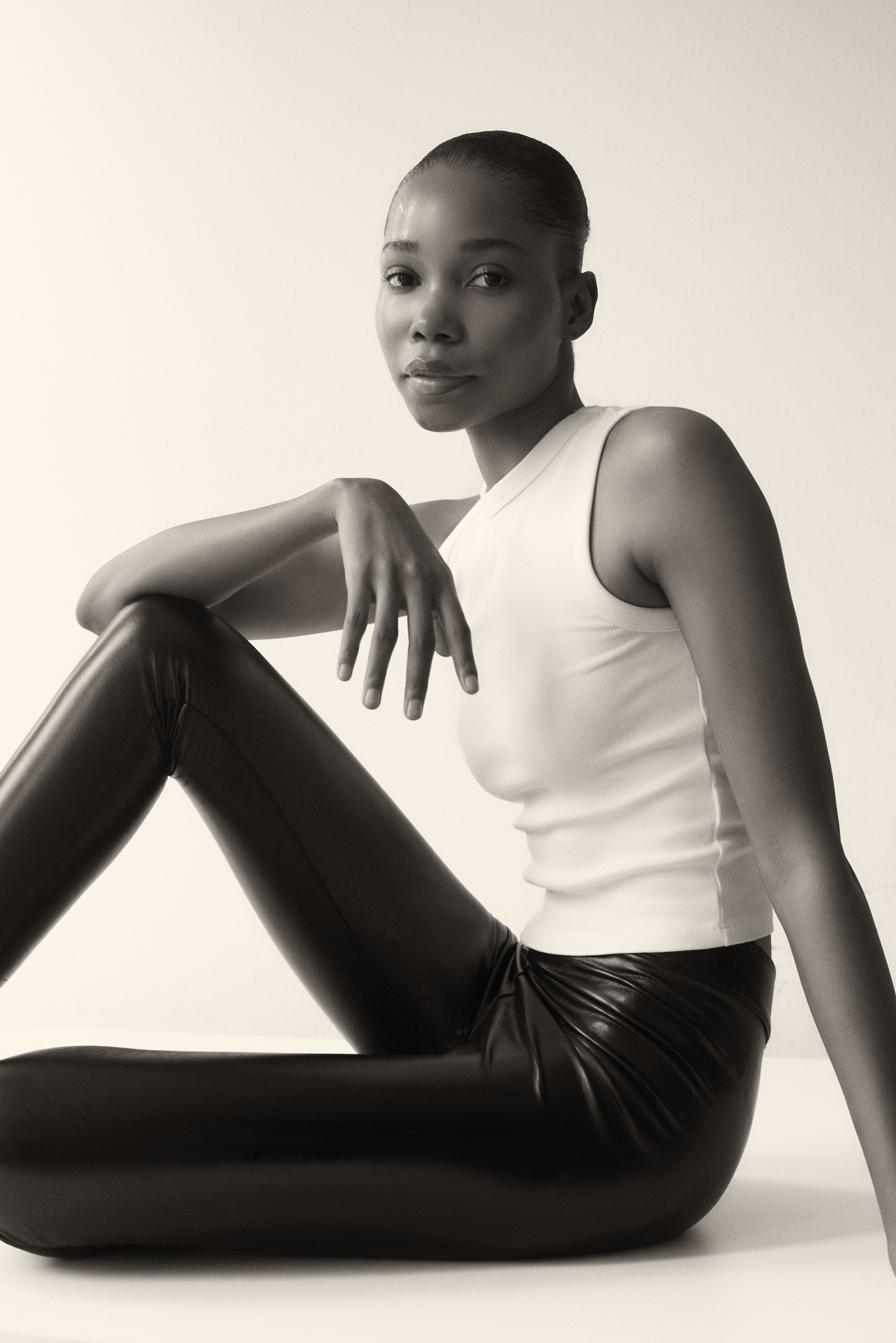 Stylish black and white portrait of a fashion model wearing leather pants, emphasizing elegance and simplicity.