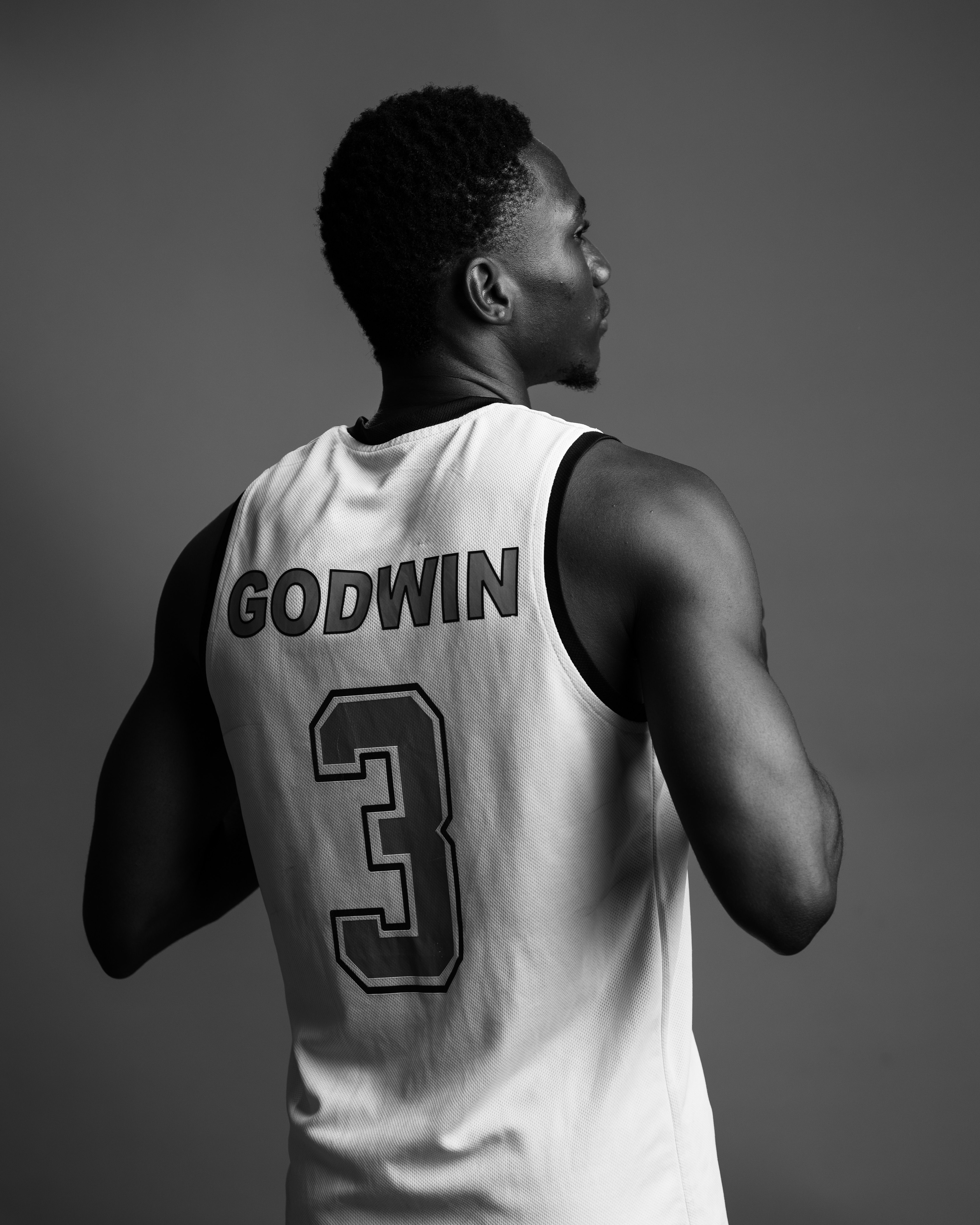 Black and white portrait of a basketball player wearing a jersey with number 3 and 'Godwin' on it, facing away.