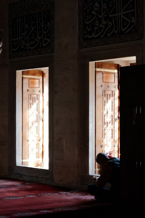 Free A person reflects in a serene, sunlit area of a mosque, highlighting architectural beauty. Stock Photo