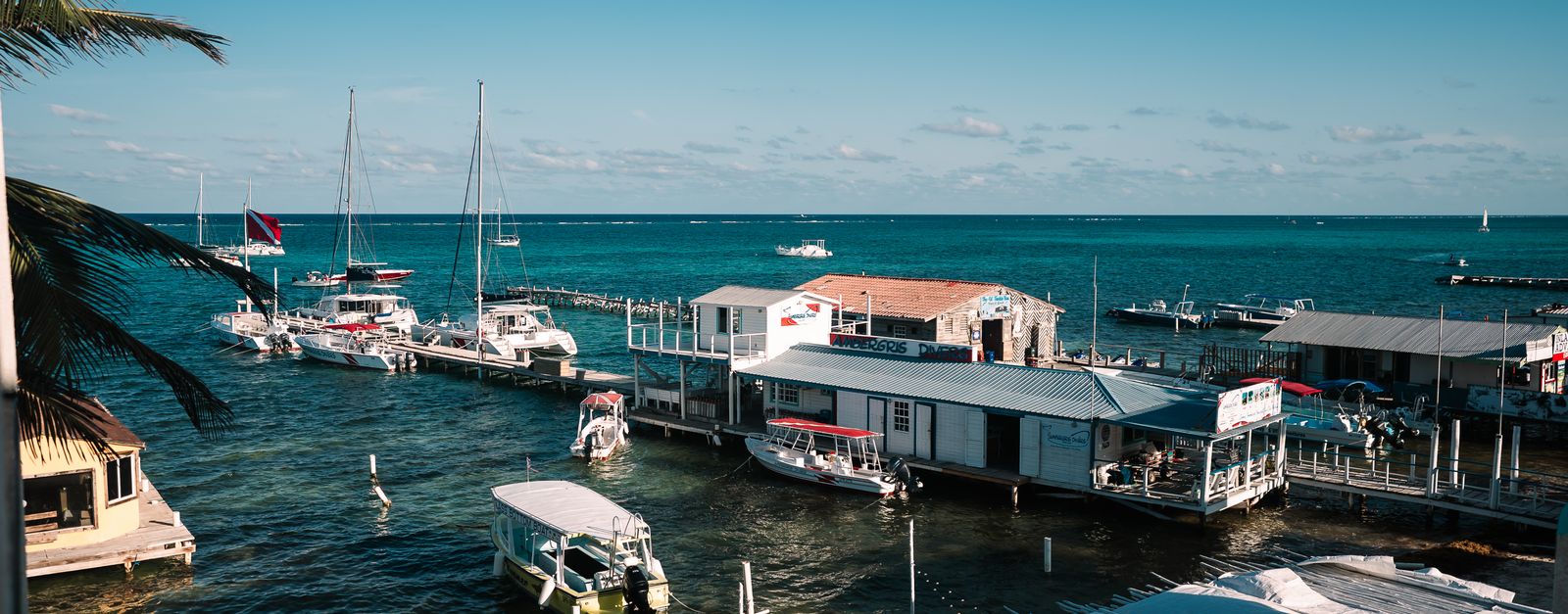 A picturesque marina with sailboats and clear blue waters under a sunny sky, offering a tranquil seaside scene.