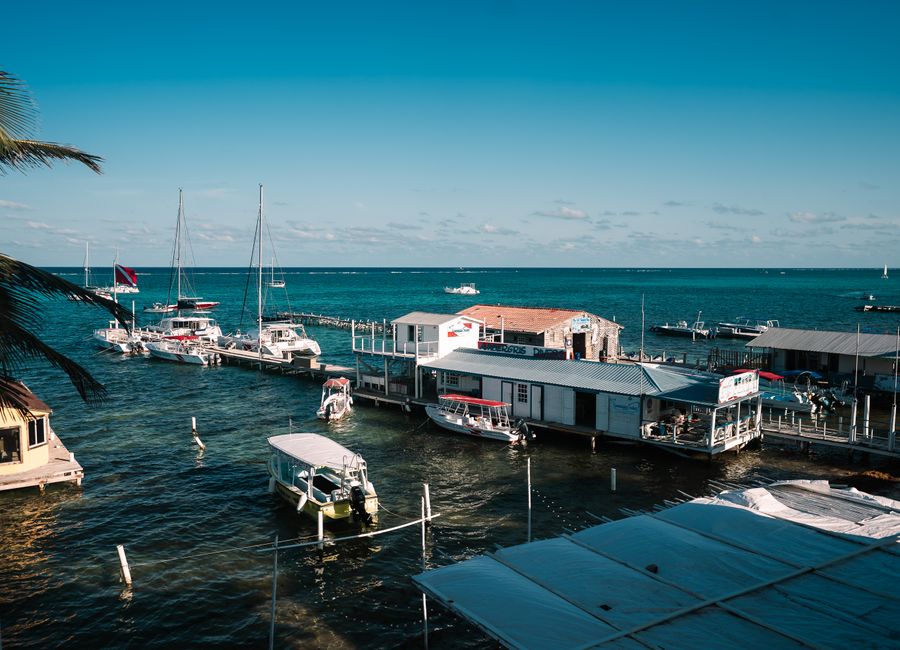 A picturesque marina with sailboats and clear blue waters under a sunny sky, offering a tranquil seaside scene.