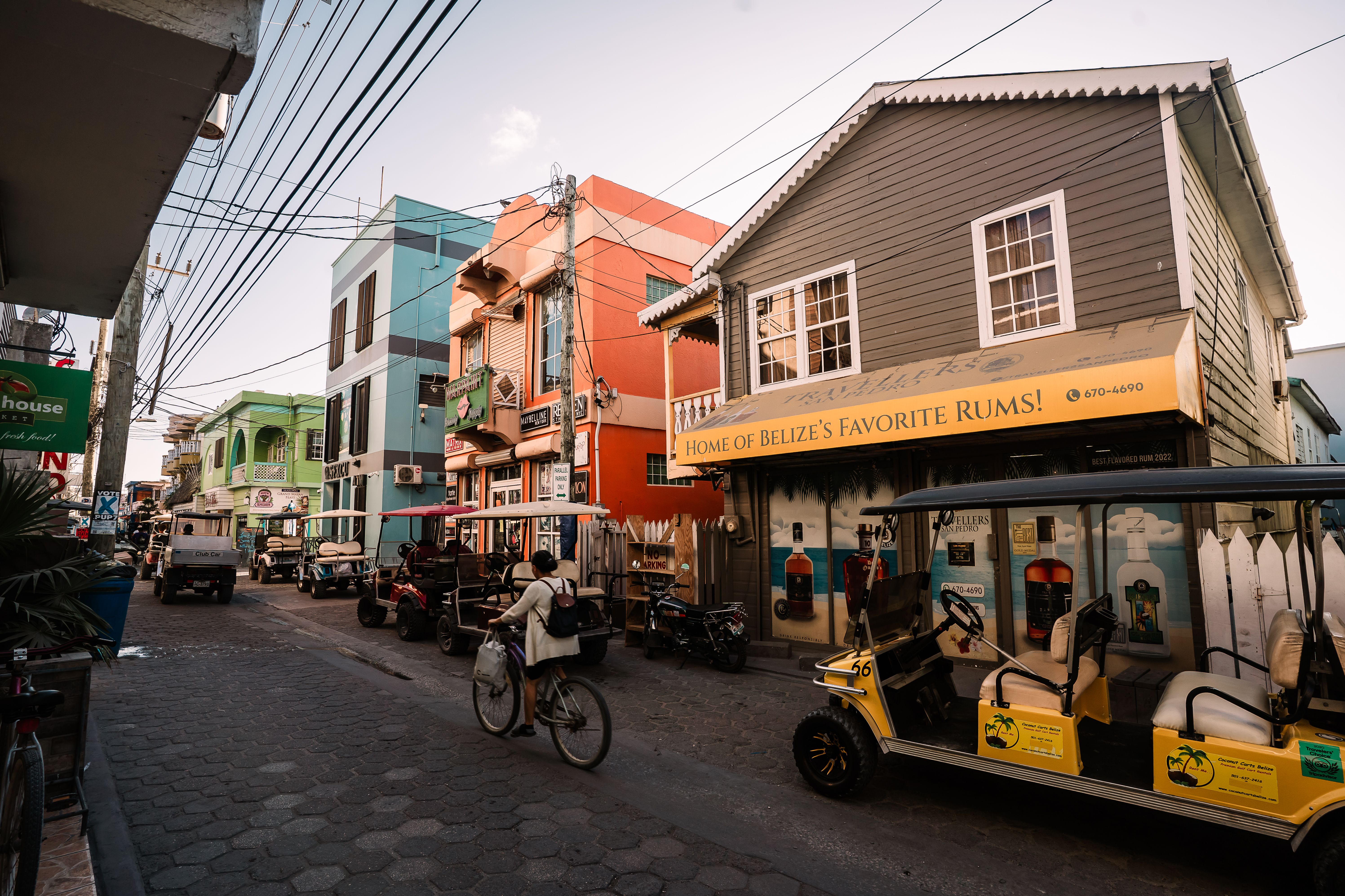 Bustling street in San Pedro, Belize featuring colorful buildings, golf carts, and a cyclist.. Photo by Roy Serafin on Pexels