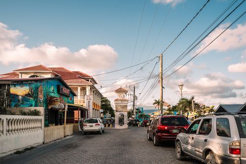 Free Sunny street scene with a clocktower and vibrant murals in Belizean town. Stock Photo