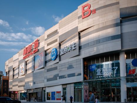 A modern shopping plaza with vibrant signage and a sunny clear sky backdrop.