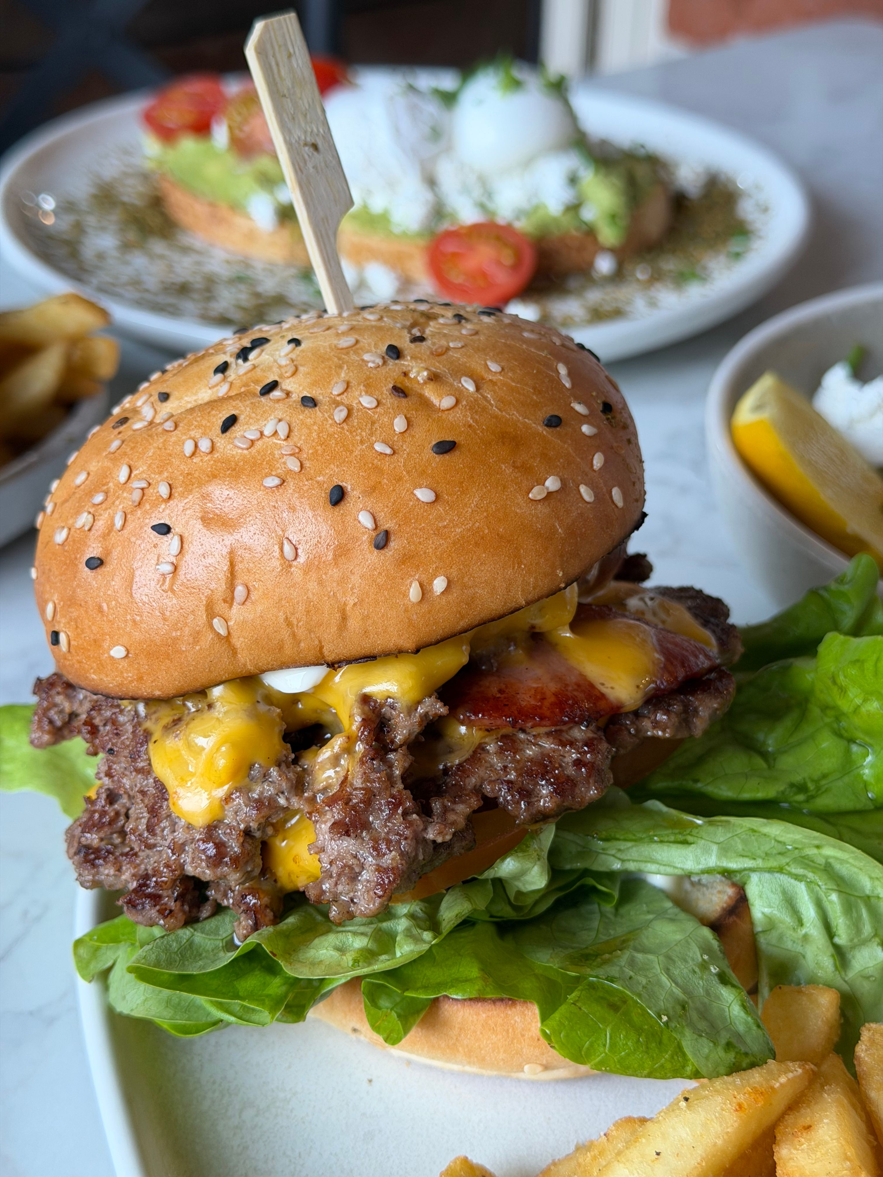 Delicious cheeseburger topped with bacon, lettuce, and cheddar. Perfect meal setting with fries.