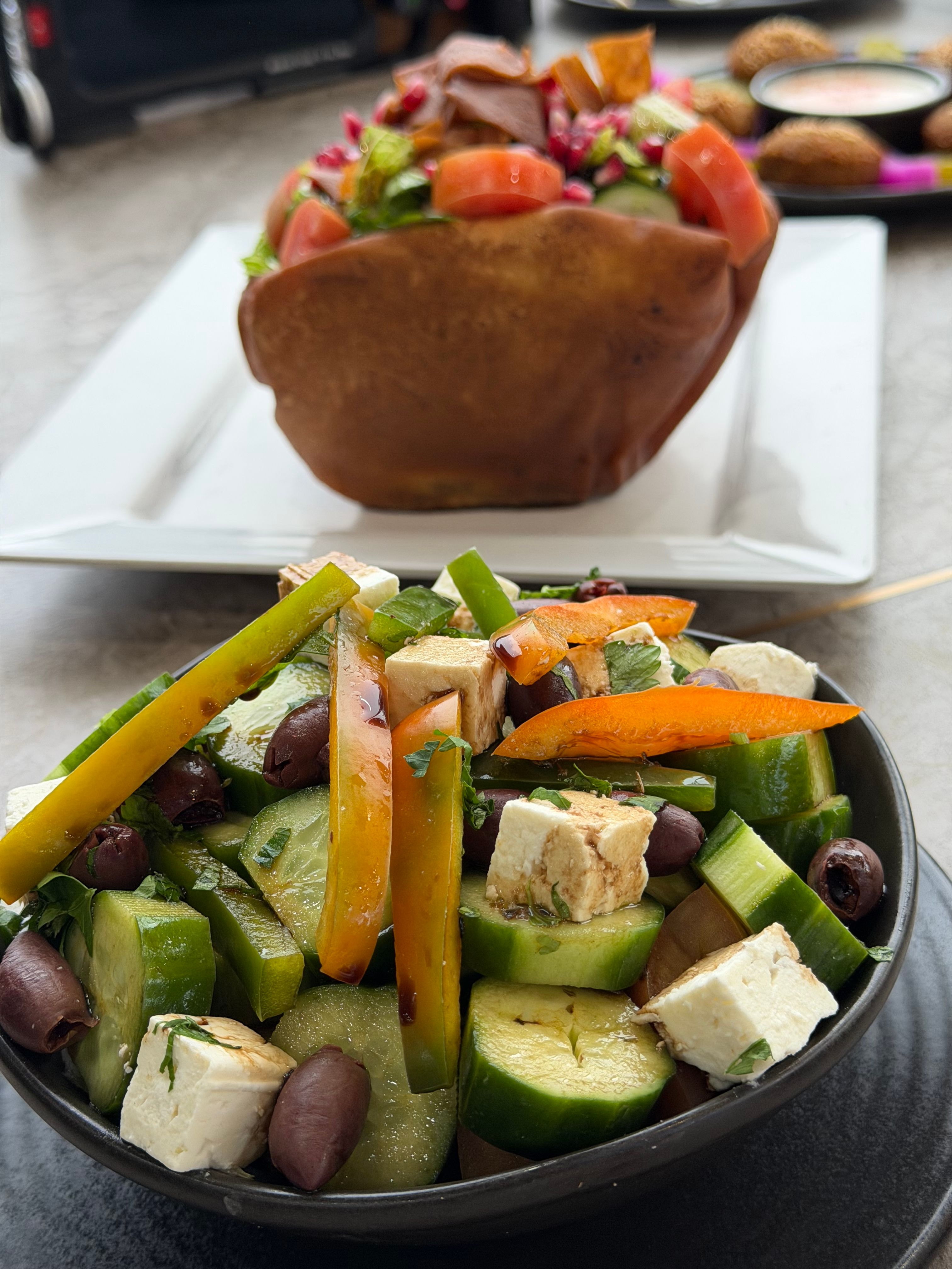 Colorful Greek salad with feta, olives, cucumbers, and peppers, served in a bowl.