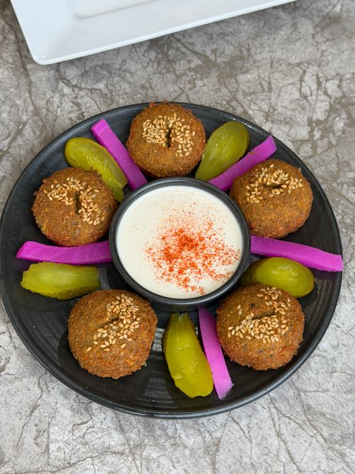 Free A beautifully arranged falafel plate with creamy dipping sauce and colorful garnishes. Stock Photo