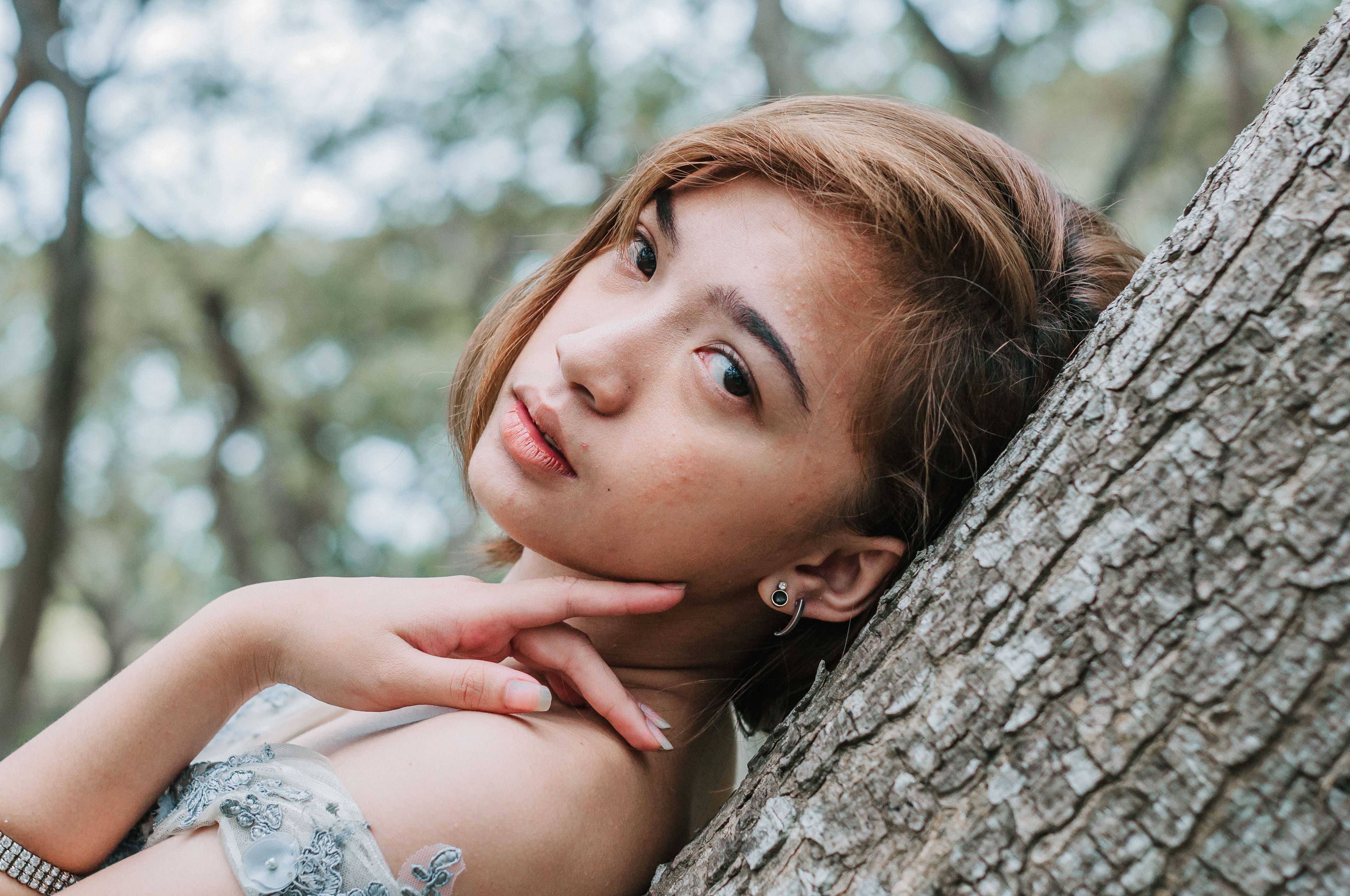 Woman in White Floral Dress Leaning on Brown Tree · Free Stock Photo