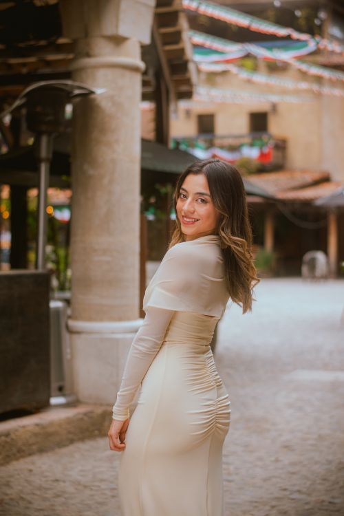 Free A young woman in a stylish dress poses gracefully in the charming streets of Val'Quirico, Mexico. Stock Photo
