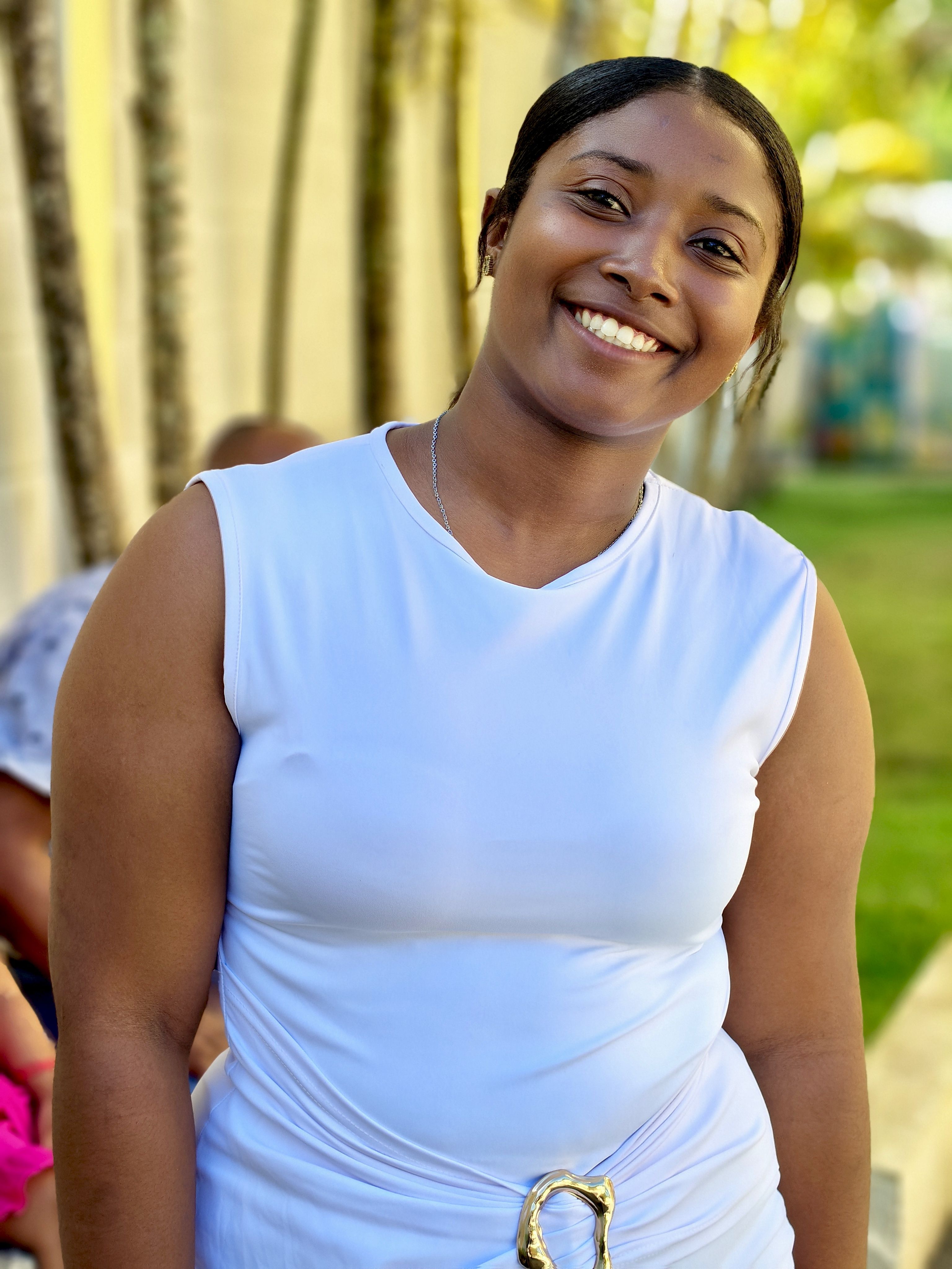 Cheerful woman in a white top smiling outdoors on a sunny day.