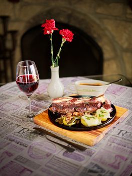 Mexican gourmet dish with a glass of red wine and flowers, set indoors.