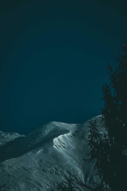 Mountain peak covered with snow against cloudless night sky