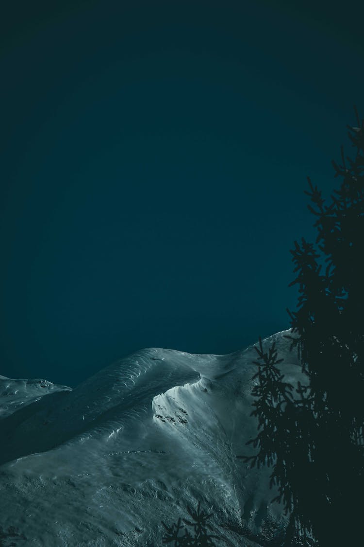 Mountain Peak Covered With Snow Against Cloudless Night Sky