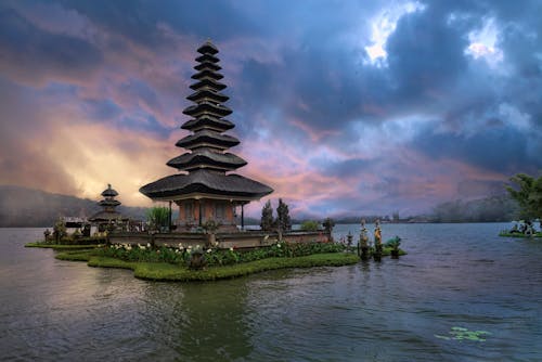 Brown and Green Temple Near Body of Water Under Blue Sky