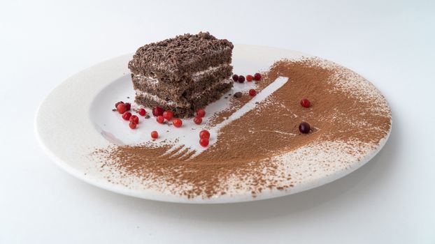 A delicious slice of chocolate cake with berries and cocoa dusting on a white plate.