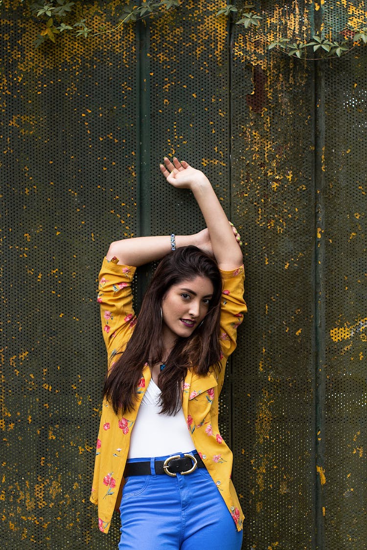 Confident Young Woman With Arms Over Head Near Weathered Fwall