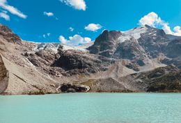 A turquoise glacier lake below bare mountains. Photo by Bhavy Ahuja on Pexels