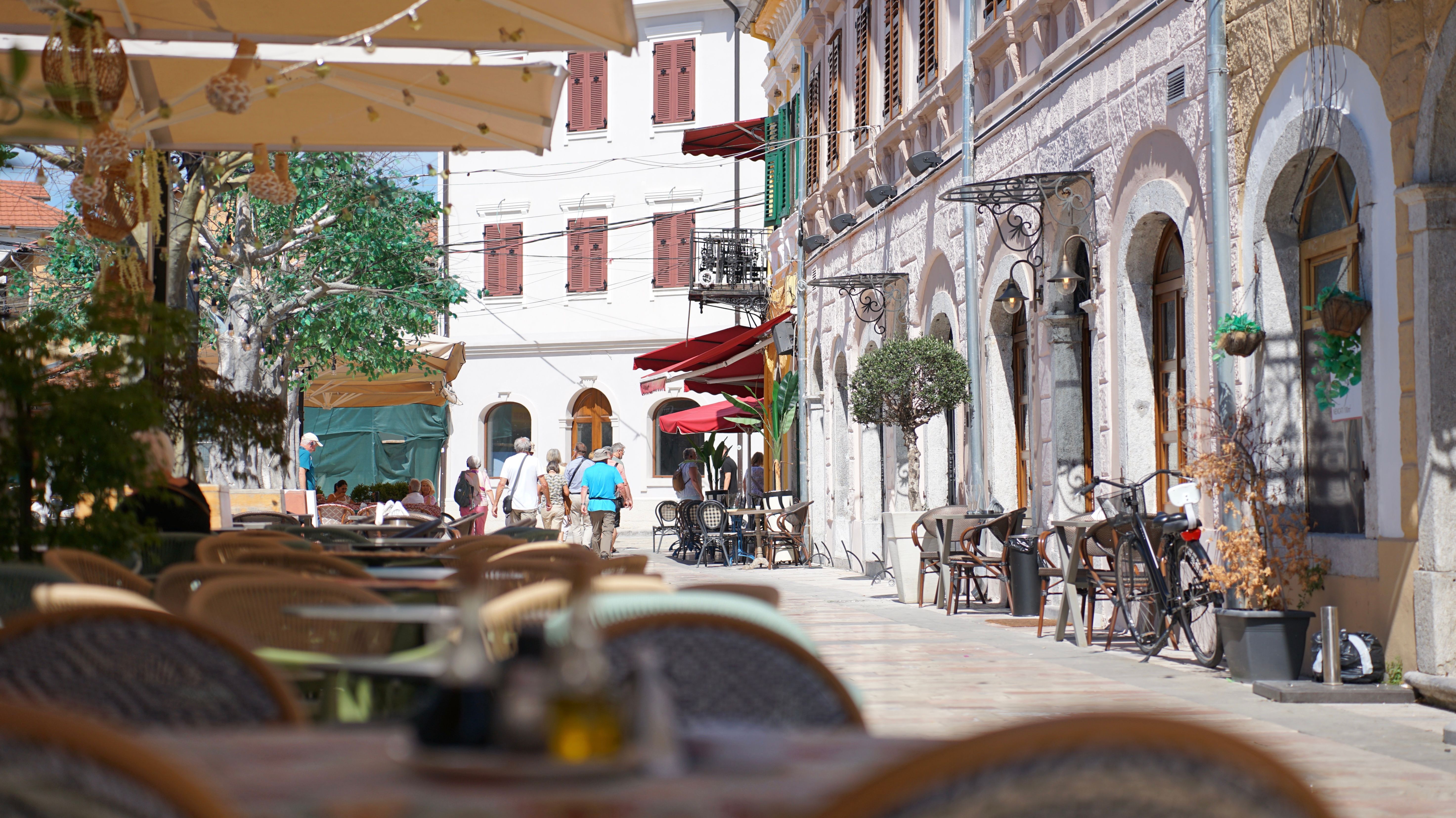 Sunny day view of street cafés in Shkodër, showcasing charming architecture and outdoor seating.
