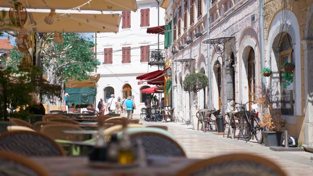 Vue ensoleillée des cafés de rue à Shkodër, mettant en valeur une architecture charmante et des terrasses.