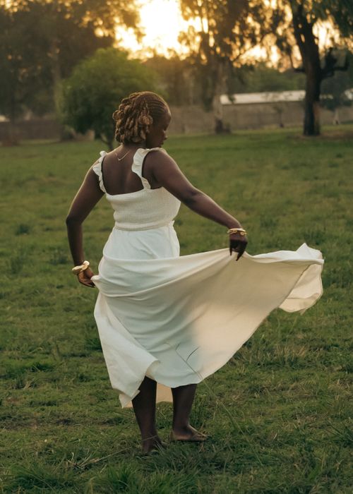 Free A woman dances gracefully in a white dress in a serene field at sunset, evoking joy and freedom. Stock Photo