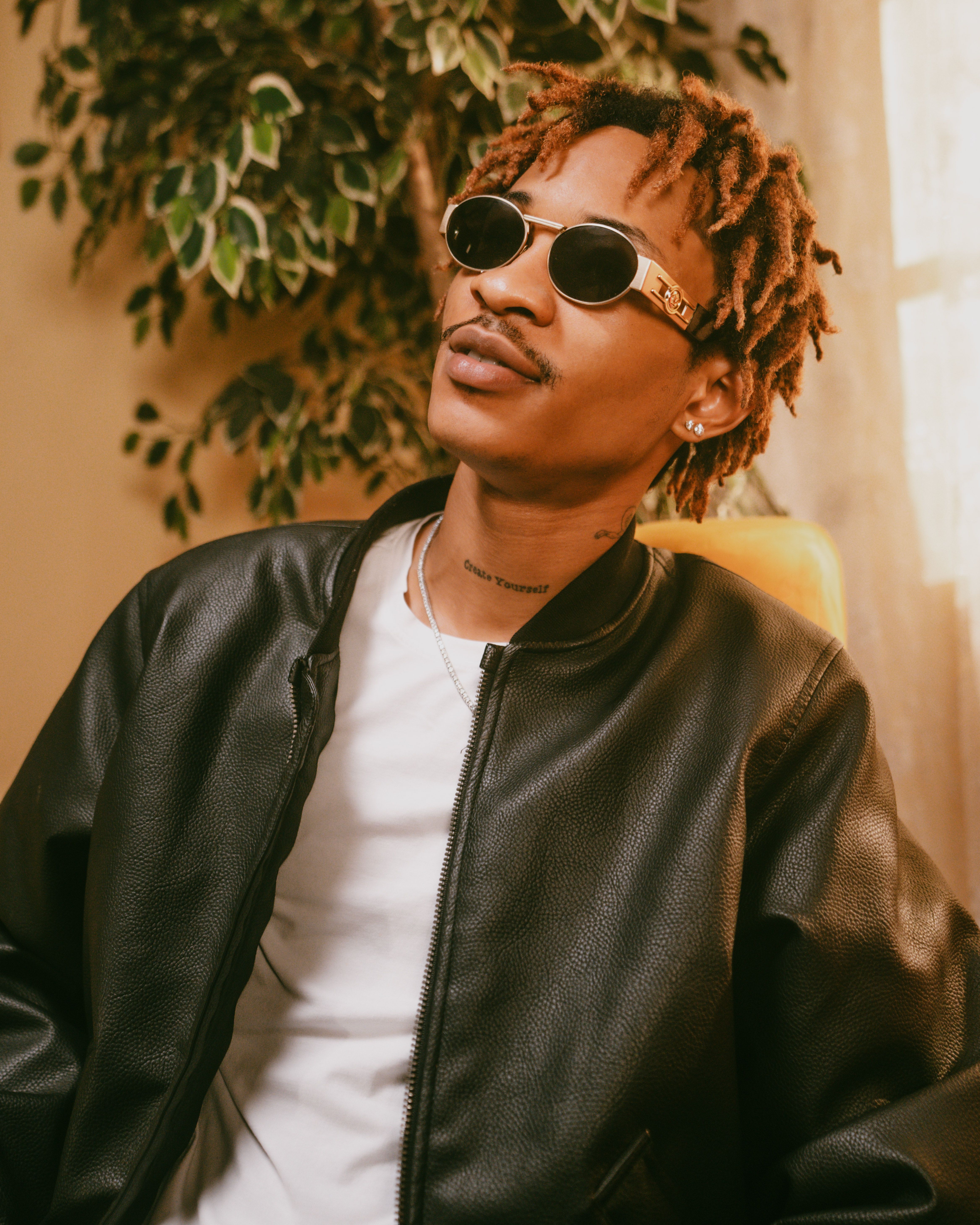 Confident man wearing sunglasses and leather jacket indoors.