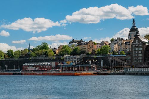 Free Scenic view of Södermalm district along Stockholm's waterfront on a sunny day with blue skies and clouds. Stock Photo