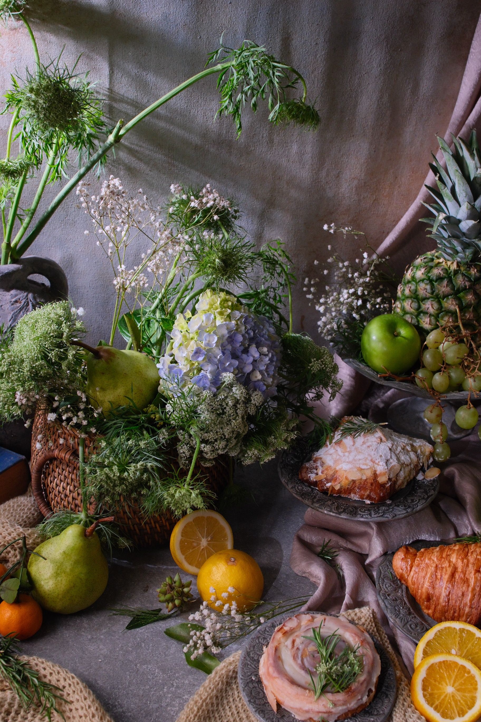 Artistic still life arrangement featuring fruits, pastries, and flowers in a cozy setting.