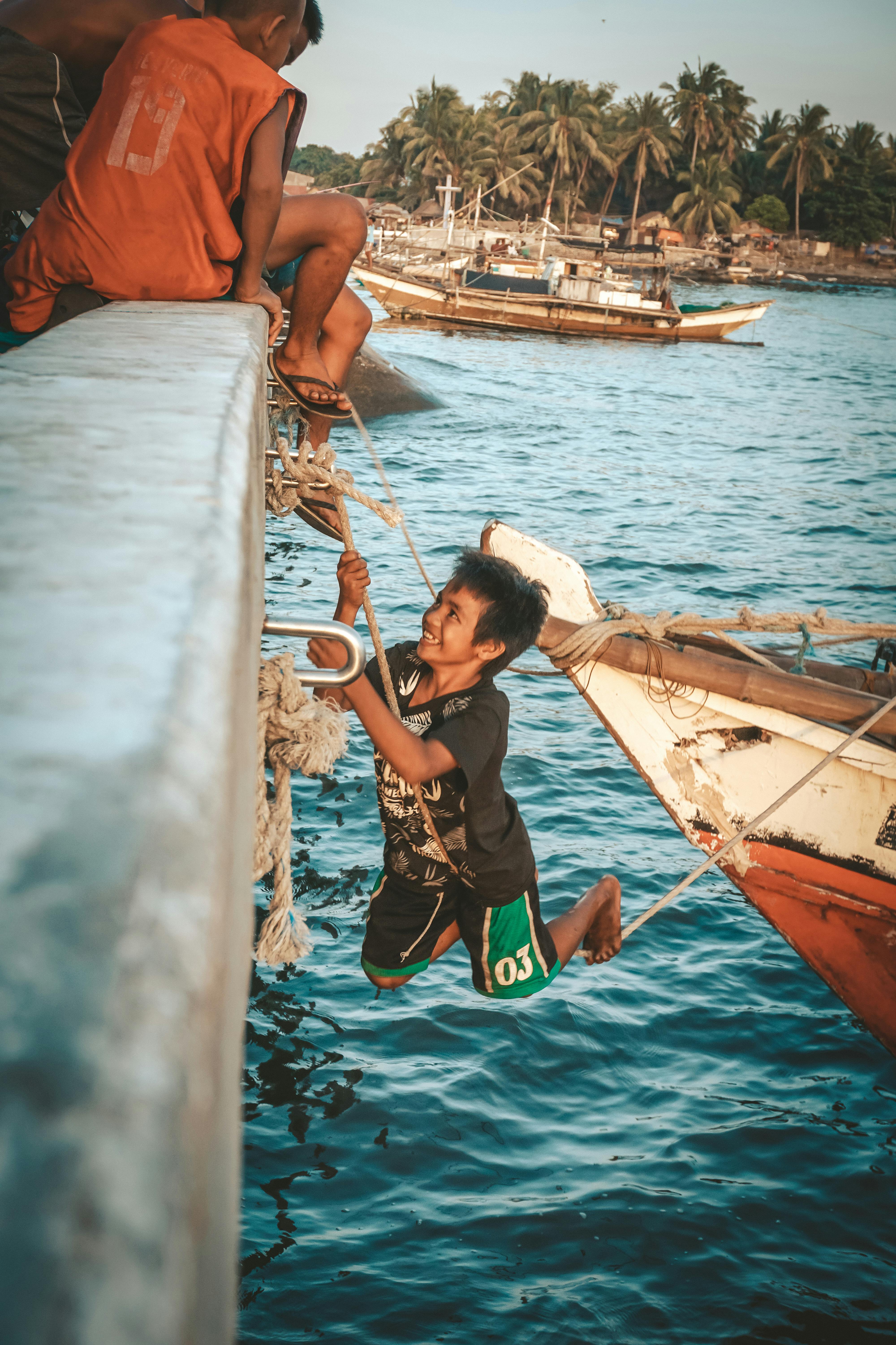 boys playing on aged boat in tropical sea