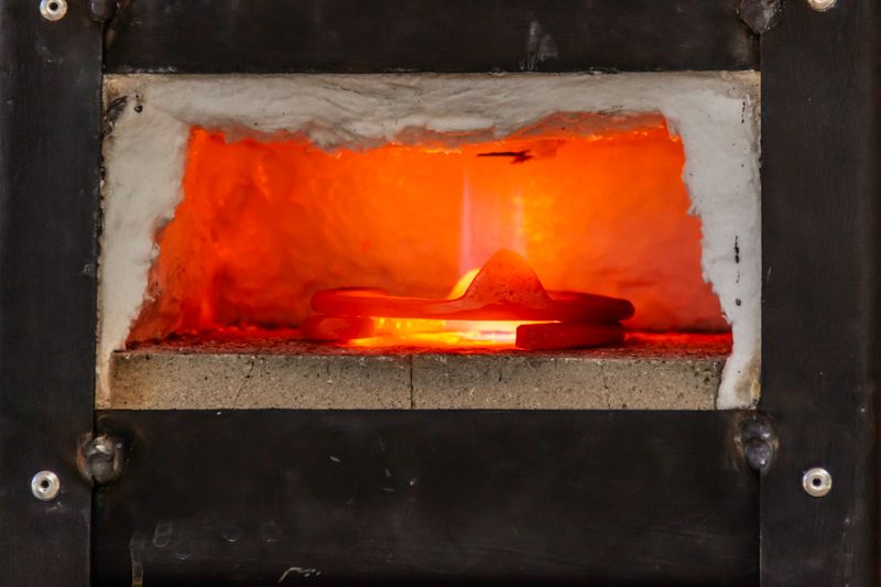 A close-up view of an industrial furnace with glowing metal heated inside