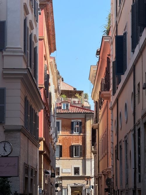 Free Explore a picturesque alley in Rome, showcasing classic Italian architecture under a clear blue sky. Stock Photo