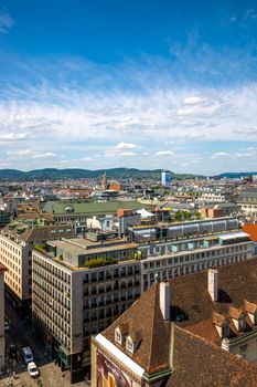 A vibrant aerial view of Zurich's rooftops and cityscape against a blue sky.