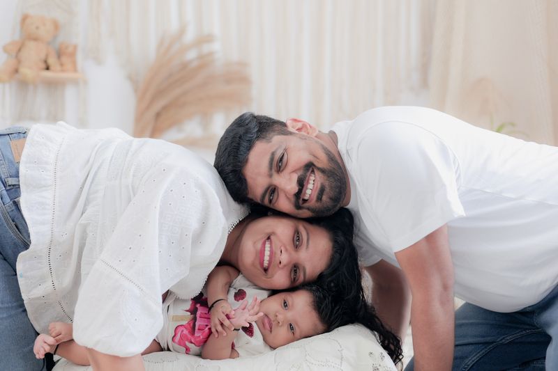 Joyful family cuddling together indoors, capturing a heartwarming moment with their baby.