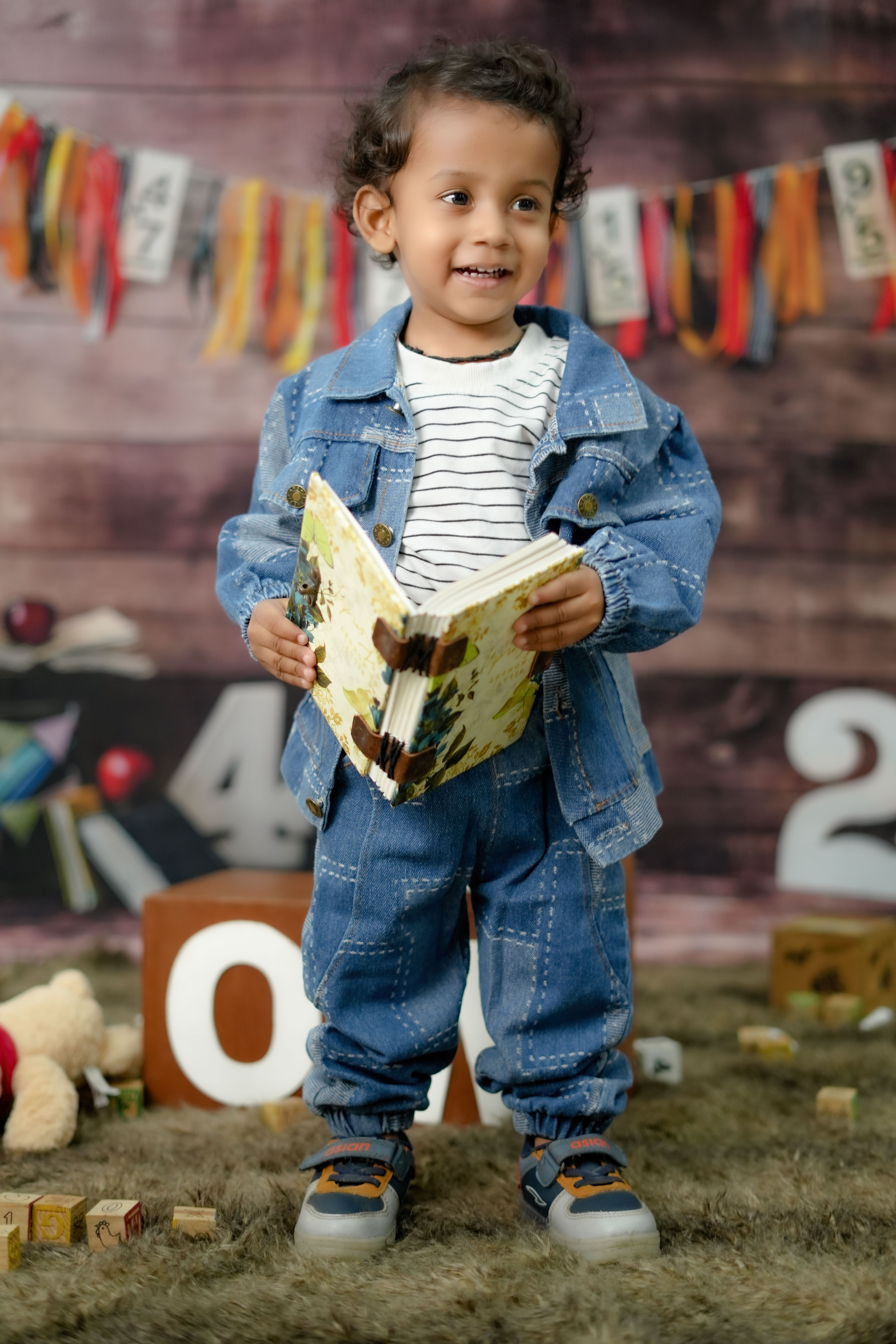 Adorable child in denim outfit enjoying a book in a colorful and playful setting.