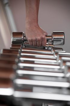 A close-up view of a hand grabbing a shiny dumbbell, representing fitness and strength training.