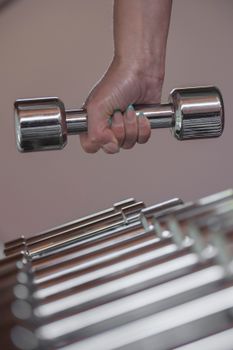 A person gripping a chrome dumbbell, emphasizing strength and fitness.